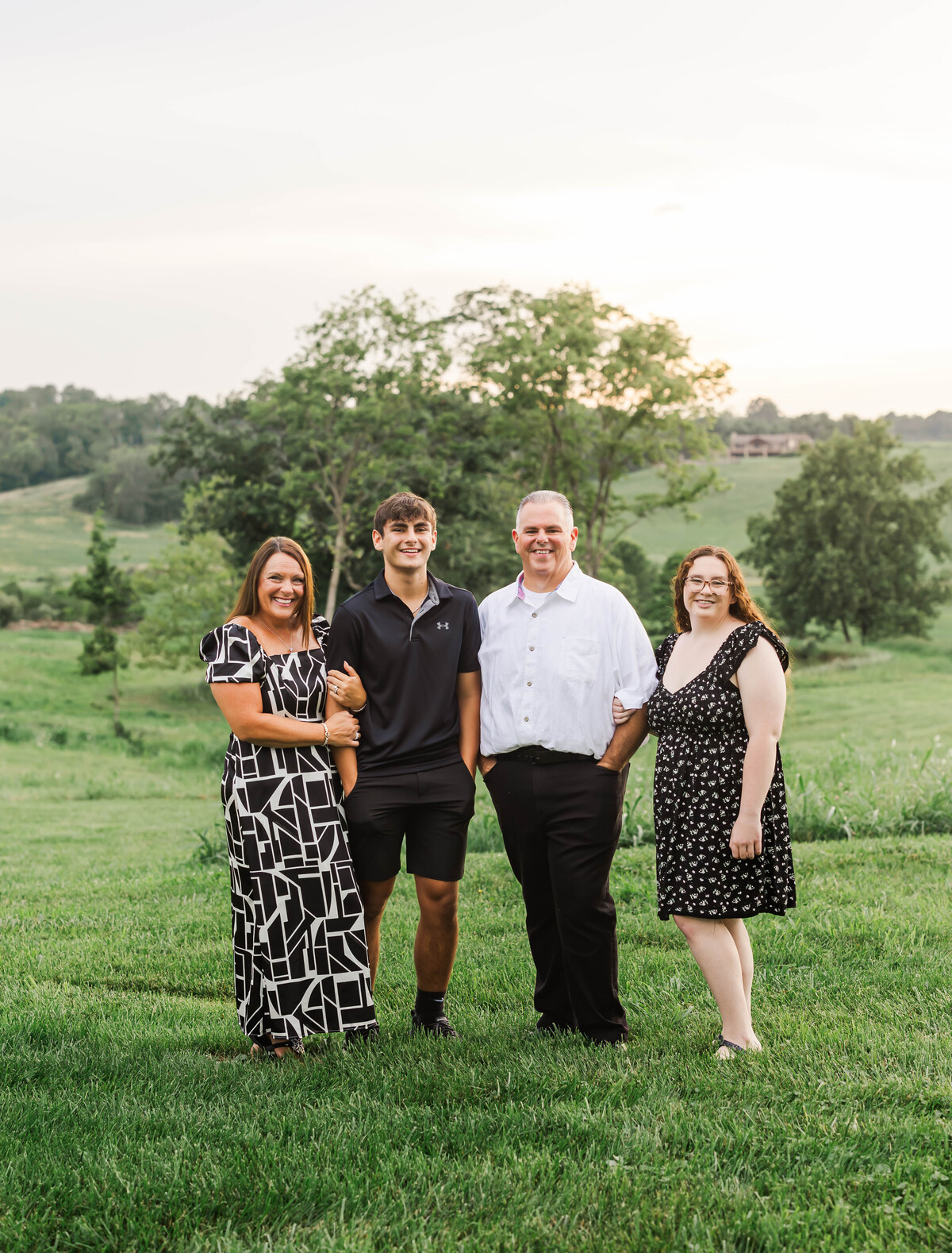 a family with a man, woman, son, and daughter posing together with trees in the background