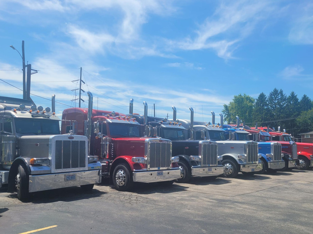 seven semi trucks parked next to each other in a parking lot
