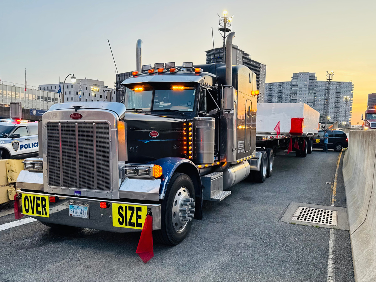 a flatbed semi truck parked on the side of a highway with an over size heavy load