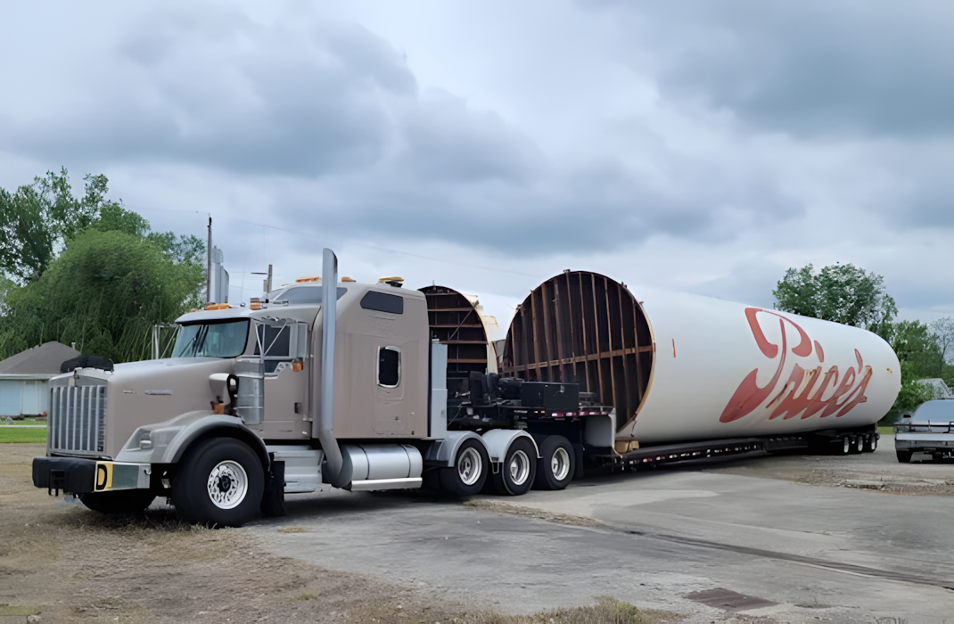 a semi truck with a flat-bed trailer hauling a heavy load parked at in a lot